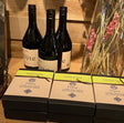 Three bottles of Flyte wine and three boxes of Davenports Flyte chocolate truffles on a wooden surface.