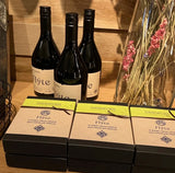 Three bottles of Flyte wine and three boxes of Davenports Flyte chocolate truffles on a wooden surface.