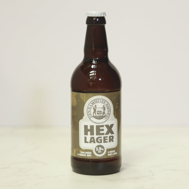Hexhamshire Brewery Hex Lager in a brown 500ml bottle with an olive-green and cream label and silver cap on a pale background