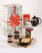 A gift hamper box with an assortment of Northumbrian products including bakehouse shortbread, traditional afternoon teabags, honey jar, and jam with mead, all presented in front of the box.