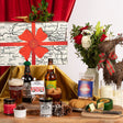 Gourmet gift set with beer, cheese, and flowers on a wooden table.
