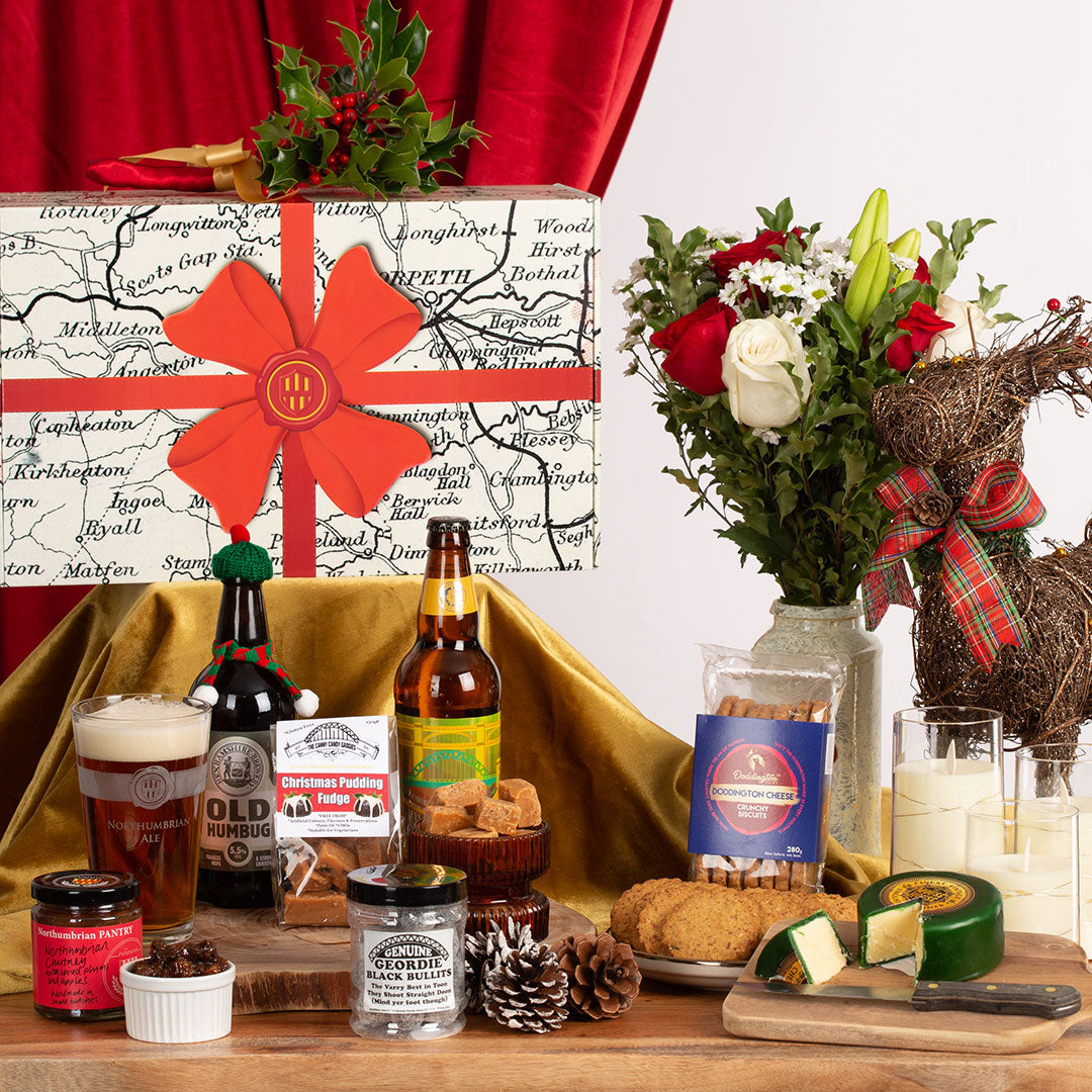 Gourmet gift set with beer, cheese, and flowers on a wooden table.