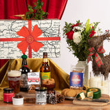 Gourmet gift set with beer, cheese, and flowers on a wooden table.