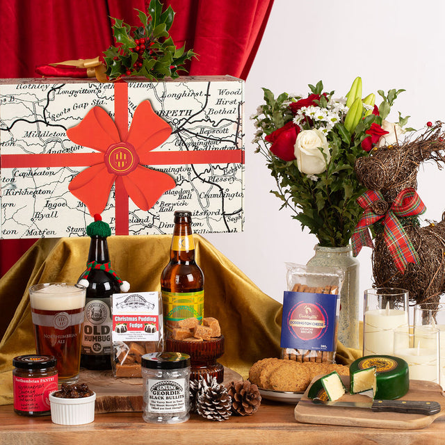 Gourmet gift set with beer, cheese, and flowers on a wooden table.