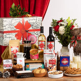 Gourmet gift basket with wine, coffee, snacks, and a decorative box on a wooden table.